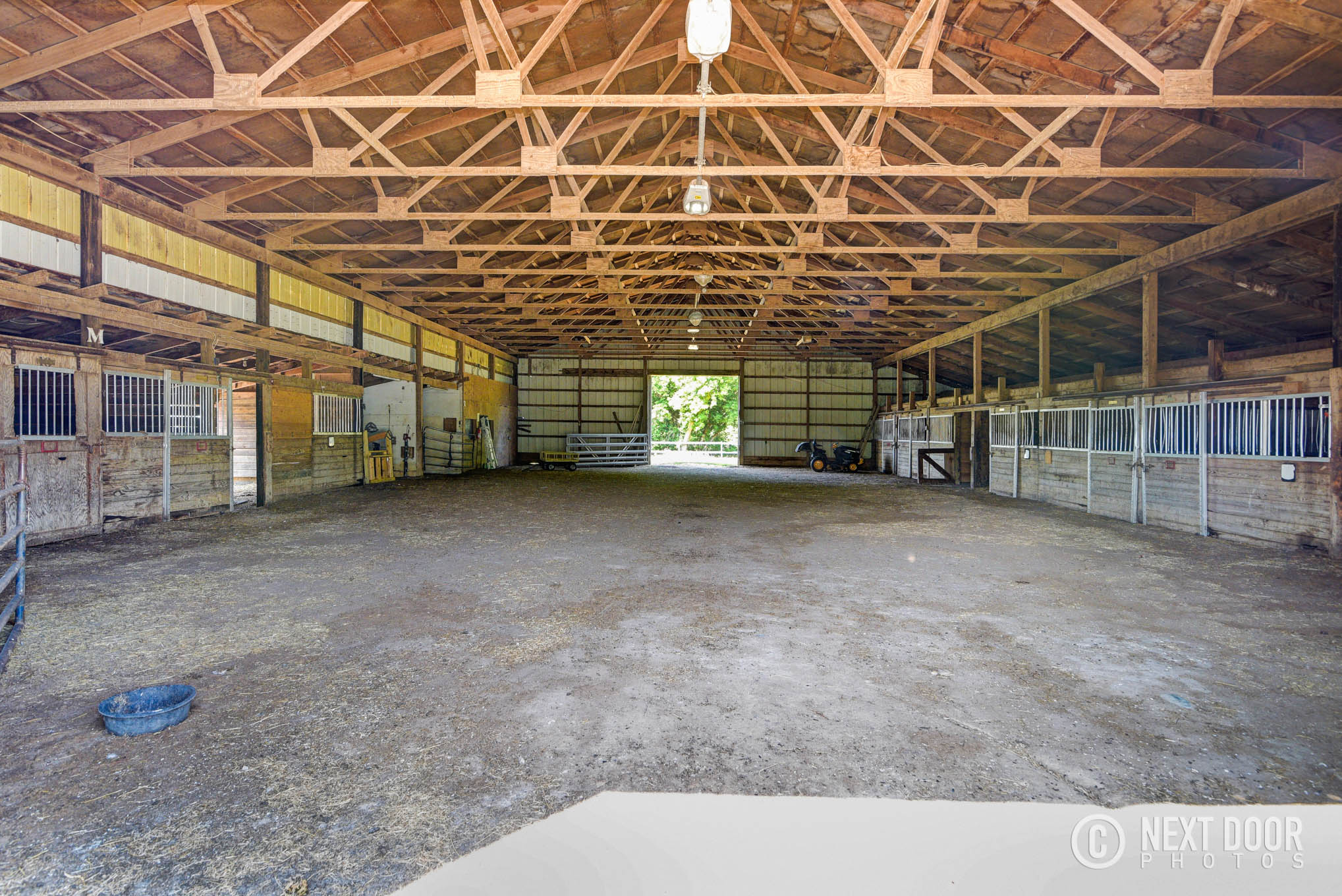 Wide barn interior with stalls at a Lansing horse boarding property